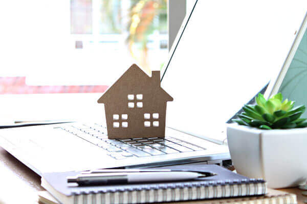 Ein Laptop auf dem ein kleines Haus aus Pappe steht